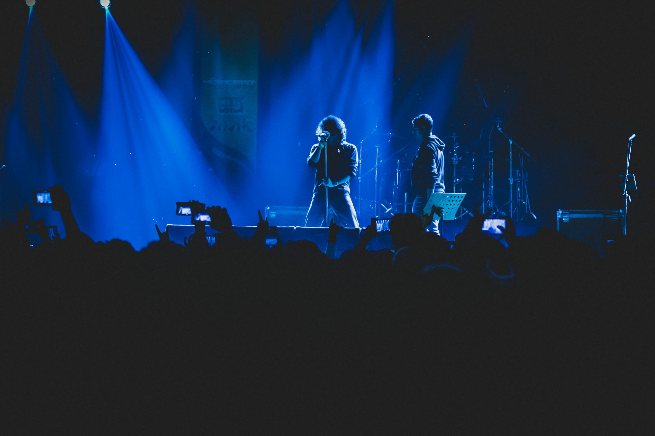 A lively concert scene with vivid lighting, featuring a singer and band on stage.